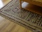 (LR) AREA RUG; TAN WITH BROWN/OLIVE GREEN ACCENTS IN A CIRCULAR/GRECIAN PATTERN. NOT FRINGED, FAIRLY