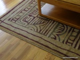 (LR) AREA RUG; TAN WITH BROWN/OLIVE GREEN ACCENTS IN A CIRCULAR/GRECIAN PATTERN. NOT FRINGED, FAIRLY