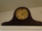 (LR) MANTEL CLOCK BY SESSIONS; RICH AND DARK WOOD IN TRADITIONAL ARCH PATTERN AND ROUND ANTIQUED TAN
