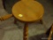 (LR) WOODEN FOOTSTOOL; LIGHT WOOD FINISH, ROUND TOP WITH THREE LEGS AND A SIDE HANDLE FOR EASY