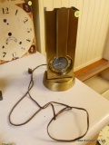 (K) VINTAGE BRASS CLOCK WITH LIGHT BULB IN BACK; VERY RETRO LOOKING, ELECTRICALLY POWERED. MEASURES