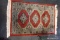 (R5) SMALL PAKISTAN AREA RUG; MADE BY AMC, HAND KNOTTED, 100% WOOL. RED WITH TAN AND BLACK BORDER