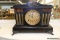 (R6) ANTIQUE SESSIONS MANTEL CLOCK; BLACK BODY WITH BRASS FACE, BROWN AND GOLD MARBLED TRIM, 3