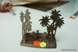 (R2) BRASS MIRAGE DECOR; HAS PALM TREES AND 4 CAMELS LYING IN THE SAND. MEASURES 4.5 IN X 2.5 IN X