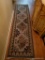 (HALL) CARPET RUNNER; TAN AND NAVY WOVEN RUNNER WITH RED AND GREEN FLORAL PRINT. HAS A NAVY AND