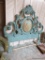 (BED) PASTEL TEAL ORNATELY CARVED HEADBOARD; CHERUB PORTRAIT IN CENTER FRAMED OVAL. BEAUTIFUL AND