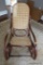 (FOY) CANE BACK AND SEAT ROCKING CHAIR; ROUNDED BACK, SOLID WOOD SCROLLING PATTERNED SIDE AND FRAME.