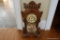 (REC) VTG WOODEN MANTEL CLOCK; MAKER UNKNOWN, CAVED DETAIL WITH GLASS FRONT DOOR. STANDS 20 IN TALL.