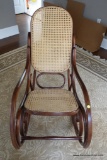 (FOY) CANE BACK AND SEAT ROCKING CHAIR; ROUNDED BACK, SOLID WOOD SCROLLING PATTERNED SIDE AND FRAME.