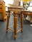 ROUND WOODEN BARSTOOL; REEDED COLUMN LEGGED WITH FOOTRESTS. MEASURES 13 IN TALL X 24 IN DIAMETER.