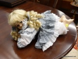 MEDIUM BABY DOLL; MEDIUM SIZED BABY DOLL LAYING DOWN WITH GRAY AND BLUE COLORED DRESS. HAS PORCELAIN