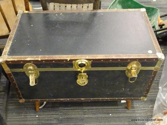 VINTAGE FOOTED TRUNK; THIS IS A BLACK TRUNK WITH RIVETS AROUND THE EDGES, TWO BRASS LATCHED AND A