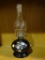 OIL LAMP; LAMPLIGHT FARMS OIL LAMP WITH CLEAR GLASS CHIMNEY, WICK, BLACK BASE WITH FLORAL DETAILING.