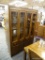 BERNHARDT CHINA CABINET; THIS LIGHTED CHINA CABINET HAS A CARVED TOP RAIL, TWO GLASS PANELED DOORS.