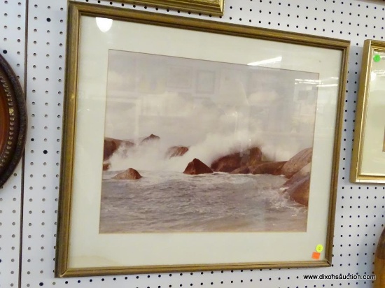FRAMED OCEAN PRINT; THIS PRINT SHOWS WAVES CRASHING ONTO ROCKS. IT IS MATTED IN WHITE AND FRAMED IN