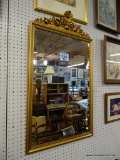 BEVELED WALL MIRROR; LARGE RECTANGULAR BEVELED MIRROR FRAMED IN A GOLD TONED FRAME WITH CARVED ROSE