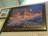 FRAMED WYOMING TRAVEL POSTER; BLACK FRAME, PHOTO IMAGE OF MOUNTAINS AND SKYLINE. MEASURES 24 IN X 27