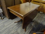 WOODEN DROP LEAF TABLE; THIS TABLE HAS TWO DROP LEAVES SITTING ATOP A TURNED PEDESTAL BASE WITH FOUR