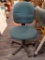 GREEN ADJUSTABLE ROLLING OFFICE CHAIR; DARK GREEN TWEED-LIKE UPHOLSTERY ON BACK AND ADJUSTABLE