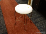 VANITY STOOL; WHITE VINYL ROUND SEAT WITH 4 HAIRPIN BRASS COLORED LEGS AND FOOT RAIL. SMALL TEARS TO