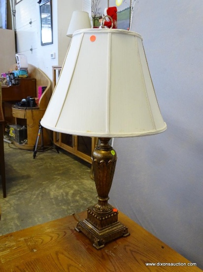 (R2) TABLE LAMP; GOLD TONED URN SHAPED TABLE LAMP WITH BELL SHAPED SHADE. HAS FINIAL. MEASURES 6.5