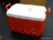 IGLOO COOLER; IGLOO RED AND WHITE 2 HANDLED COOLER WITH INCHES/CENTIMETERS MEASURING CHART ON TOP.