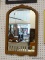 FRAMED MIRROR; HAS A CURVED TOP WITH SQUARE BASE. IS IN A WOODEN FRAME AND MEASURES 18 IN X 28 IN
