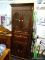 BERNHARDT DARK STAINED STORAGE/BAR CABINET; CROWN MOLDED TOP OVER PAIR OF BOWED TOP GLASS FRONT