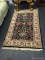 ORIENTAL STYLE RUG; BLACK IN COLOR WITH OFF WHITE, MAUVE, AND LIGHT BLUE PATTERN. HAND WOVEN FLORAL