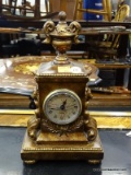 BRONZE TONED QUARTZ CLOCK; HAS A URN STYLE FINIAL WITH LIONS HEAD AND ACANTHUS LEAF CARVED SIDES.