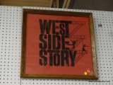 FRAMED WEST SIDE STORY PRINT; THIS PRINT HA S A RED BACKGROUND WITH BLACK WRITING. IT SAYS 