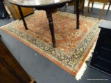 RUST/BLUE/TAN FRINGED AREA RUG; REDDISH COLORED BODY OF RUG WITH FLORAL BORDER AS WELL AS CENTER