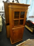 PINE FARMHOUSE CABINET; CROWN MOLDED TOP OVER A GLASS FRONT SINGLE DOOR WITH LEFT SIDE ROUND WOODEN