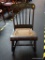 VINTAGE TOLE PAINTED ROCKING CHAIR WITH CANE SEAT; STAINED BLACK IN COLOR WITH SCALLOPED TOP RAIL,