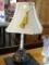 TABLE LAMP; CANDLESTICK STYLE TABLE LAMP WITH BRASS BASE. HAS SHADE AND FINIAL AND MEASURES 22 IN
