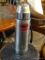 THERMOS; UNBREAKABLE UNO-VAC STAINLESS STEEL THERMOS WITH BUILT IN HANDLE. MEASURES 13 IN TALL