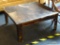 (BACK) SQUARE WOODEN COFFEE TABLE; WOODEN COFFEE TABLE WITH A SQUARE TOP AND ANGLED BLOCK LEGS. THIS