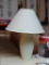 (BACK) CREAM COLORED TEXTURED TABLE LAMP; THIS TABLE LAMP HAS A CREAM COLORED BELL SHAPED SHADE THAT