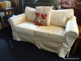 PALE YELLOW SLIPCOVERED LOVESEAT; PILLOW BACK STYLE WITH 2 SEAT CUSHIONS, ROLLED ARMS, AND A FLAT