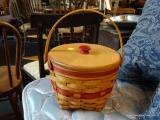 LONGABERGER 2 HANDLE BASKET; RED AND TAN IN COLOR AND HAS A PLASTIC LINER. MEASURES 7 IN X 9.5 IN X
