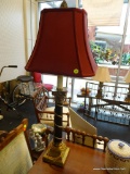 BRASS COLUMN STYLE LAMP; RED SQUARE SHAPED SHADE SITTING ON A BRASS AND BLACK COLUMN STYLE BODY WITH