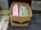 BASKET FULL OF ASSORTED LINENS; THIS RECTANGULAR BASKET HAS A HANDLE ON EACH SIDE. IT IS FILLED WITH