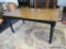 VINTAGE WOODEN FARMHOUSE TABLE; SEATS UP TO 6. SOLID WOOD PIECE WITH FINISHED TOP SURFACE AND BLACK