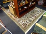 AGRA AREA RUG; SAGE GREEN, BROWN, AND TAN PATTERNED FRINGED AGRA RUG WITH CREAM COLORED FRINGE.
