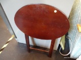 WOODEN FOLDING TABLE; RICH BROWN WOOD GRAIN FOLDING TABLE WITH OVAL TOP. THIS TABLE SITS ON 4