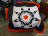 THROW QUILT; IS RED, BLACK, AND GRAY IN COLOR AND HAS A STAR PATTERN MADE INTO IT. IS IN VERY GOOD