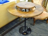 LAZY SUSAN TABLE; HAS AN ELEVATED CENTER AND BLACK PEDESTAL BASE. MEASURES 28 IN X 32 IN. IN