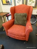 VINTAGE RED UPHOLSTERED WINGBACK CHAIR; CAMELBACK WITH ROLLED ARMS, PIPED TRIM, AND ROUND FLUTED