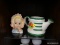 ASSORTED DECOR LOT; THIS 2 PIECE LOT INCLUDES A GREEN AND WHITE CERAMIC WATERING CAN, AND A STATUE
