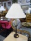 CANDLESTICK STYLE LAMP; BROWN/BLACK COLORED CANDLESTICK STYLE LAMP WITH WHITE PLEATED SHADE AND